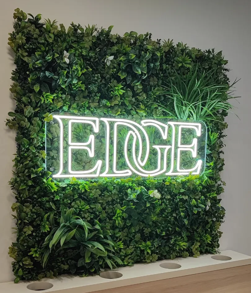 Enseigne néon LED EDGE sur un mur végétal dans un salon de coiffure